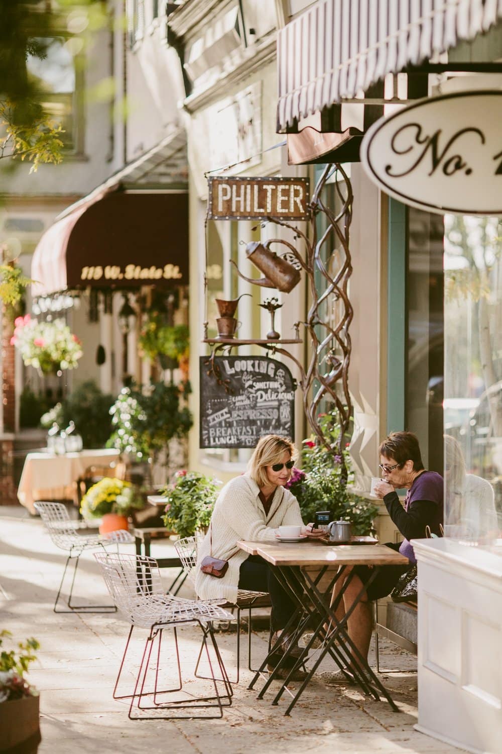 Zwei Frauen unterhalten sich beim Kaffee am Außentisch des Café Philter in Kennett Square