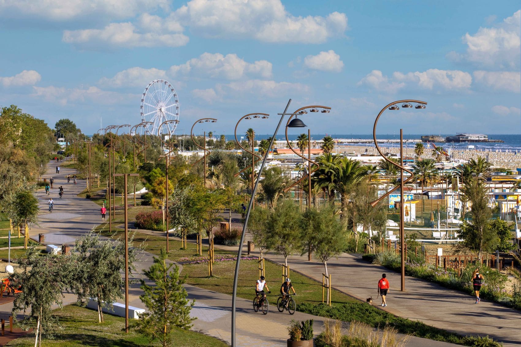 Panoramaaufnahme des Parco del Mare in Rimini; auf den Wegen im Park sind einige Menschen auf Fahrrädern unterwegs, andere joggen
