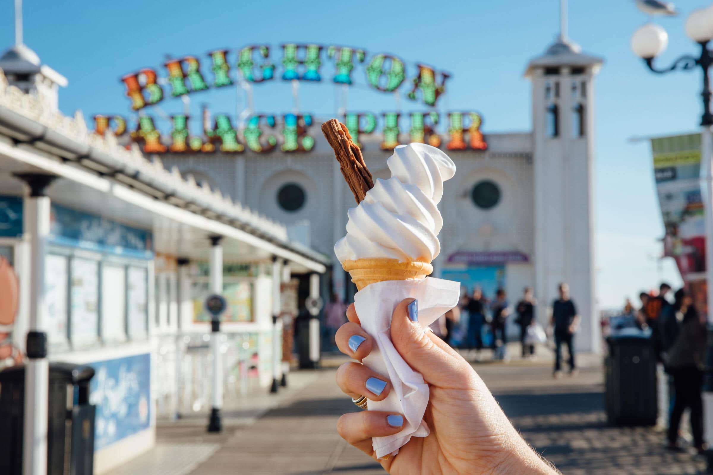 Eine Frau hält ein Eis am Brighton Pier.