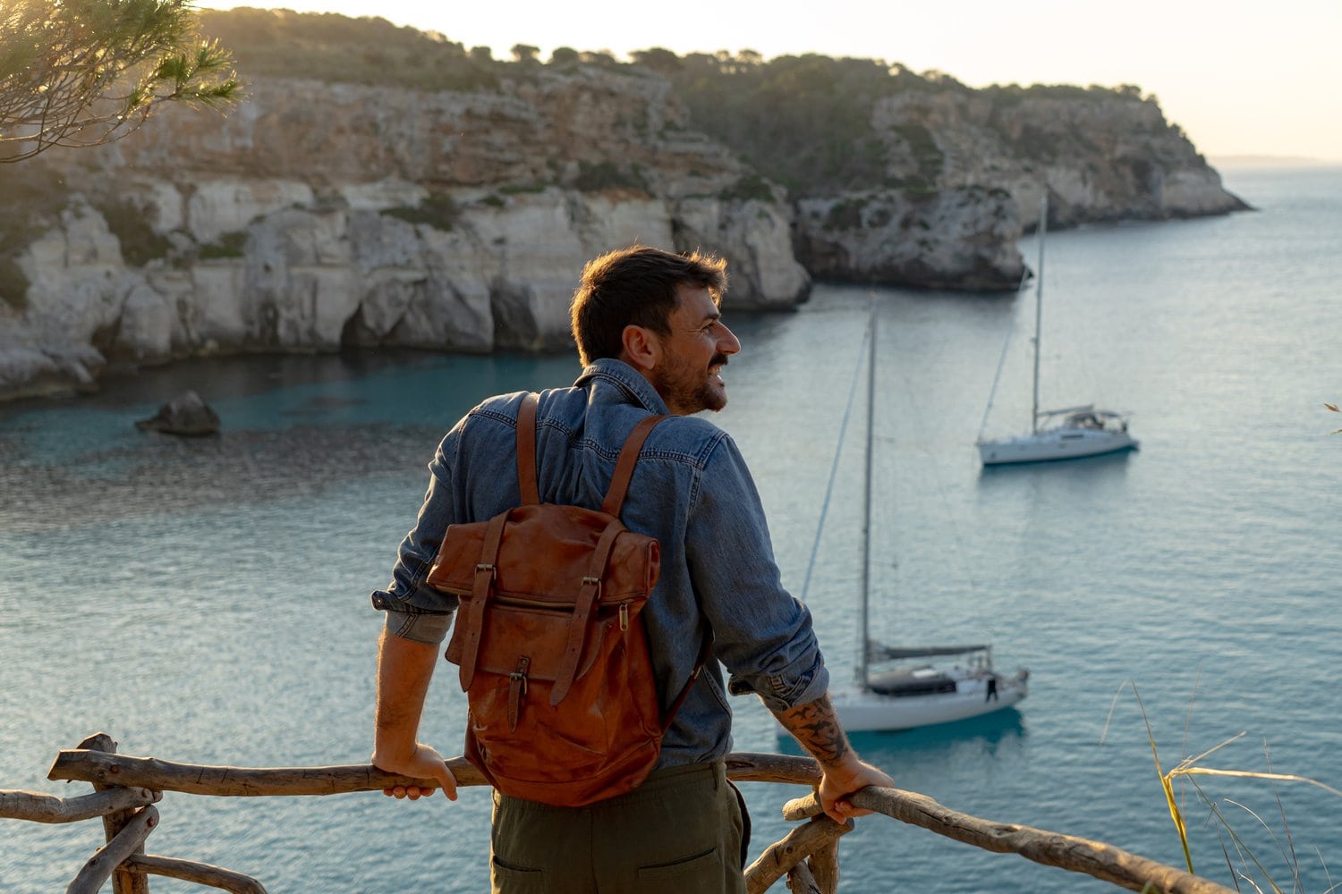 Drohnenaufnahme der Cala Macarella mit kristallklarem türkisblauen Wasser, weißem Sandstrand und Pinienhängen, ein einzelnes weißes Boot ankert in der Bucht. Foto: we-bond-creations / Shutterstock