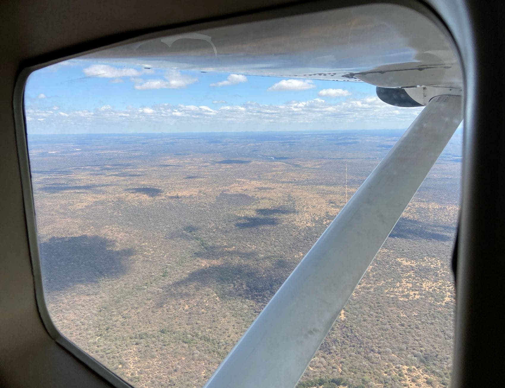 Blick auf die afrikanische Savanne aus dem Fenster eines kleinen Flugzeugs