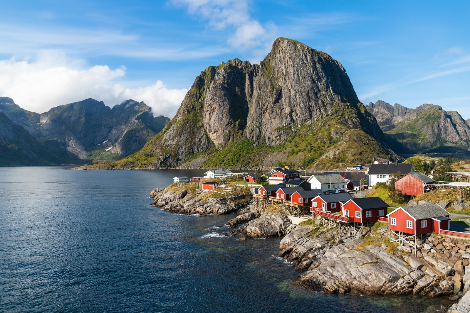 Rote Rorbuer-Fischerhütten von Hamnøy am Fjord vor dem markanten Bergmassiv der Lofoten in Norwegen