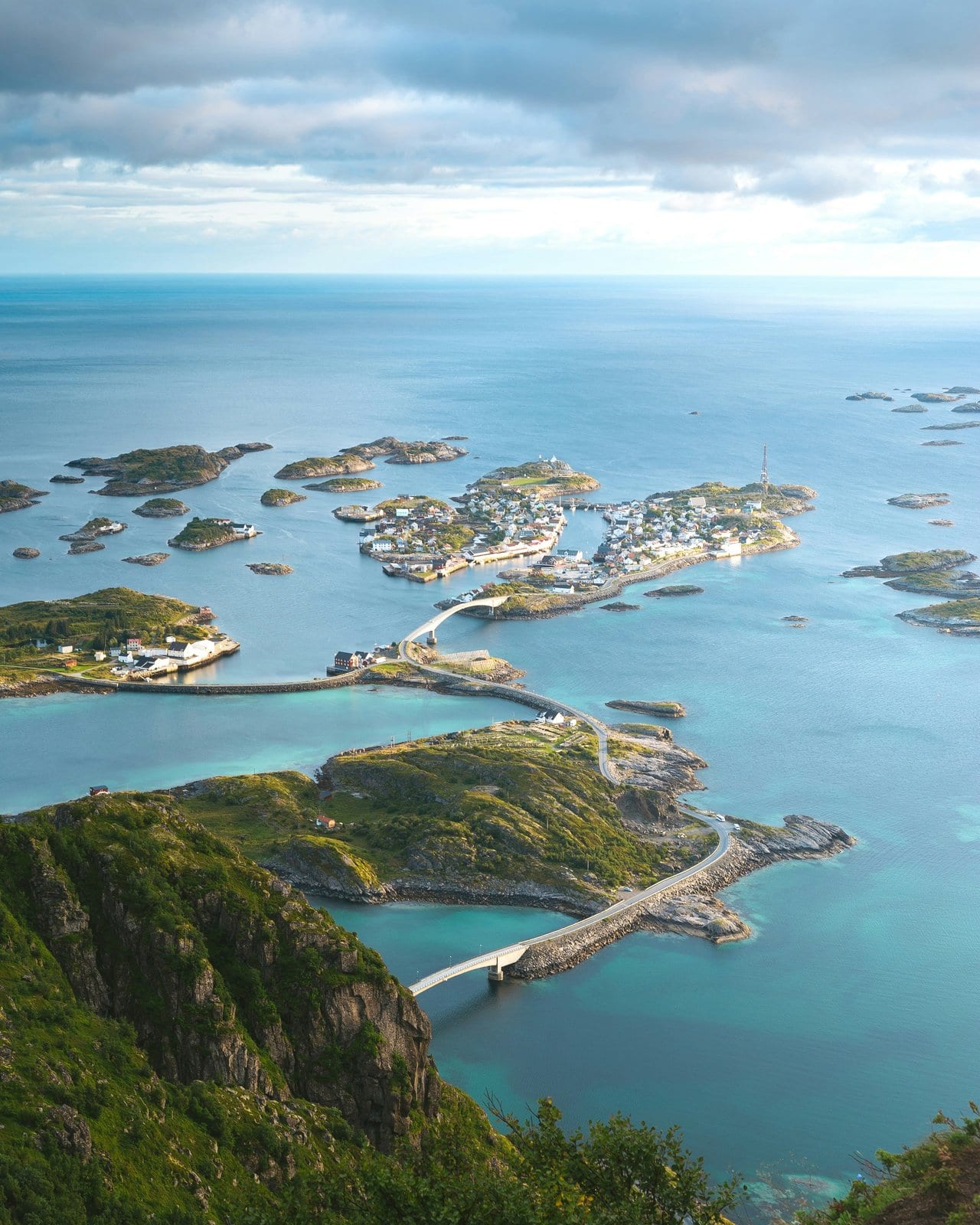 Luftaufnahme von Henningsvær auf den Lofoten mit Brücken zwischen Inseln im türkisfarbenen Nordmeer