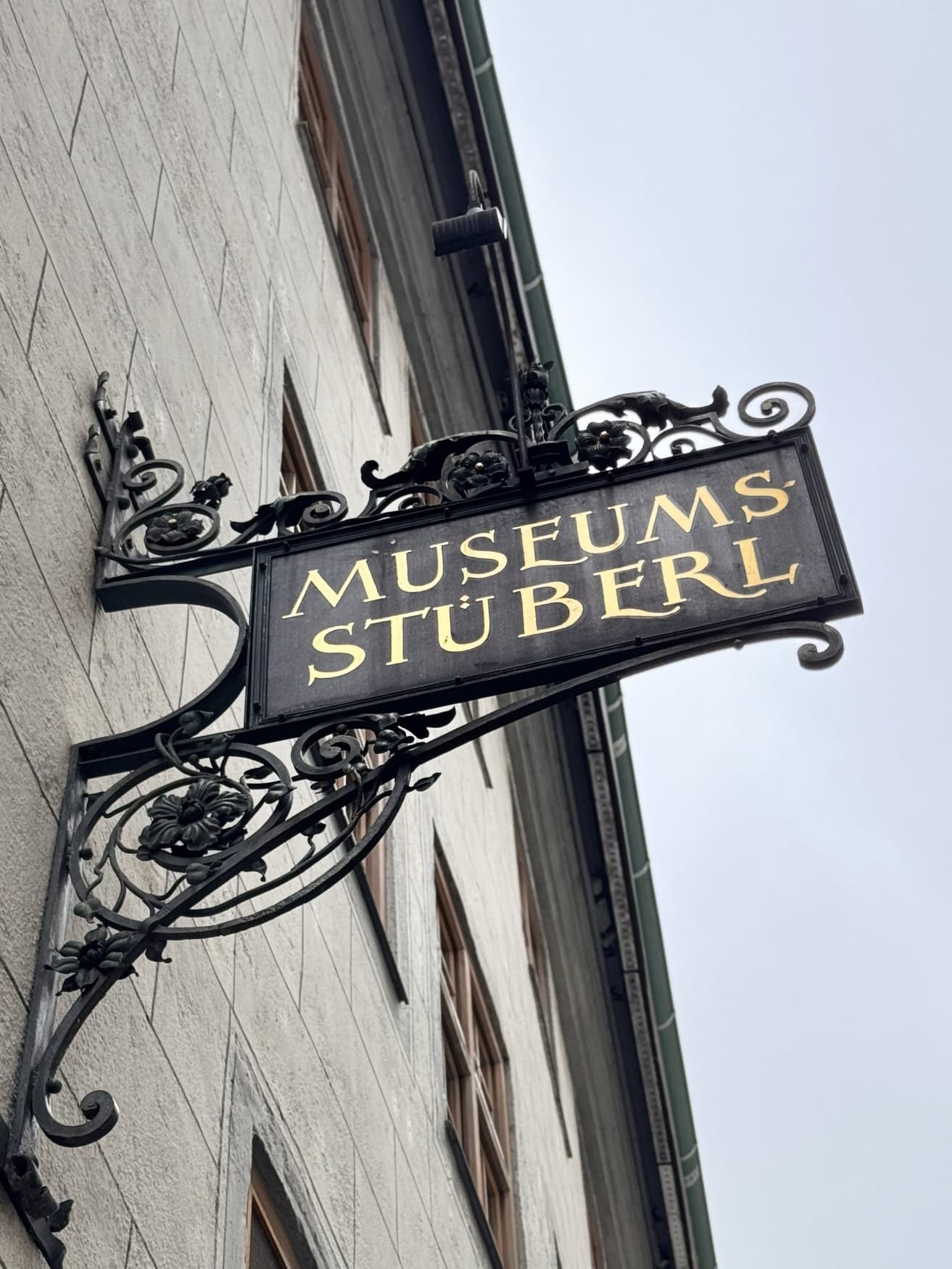 An einer Hauswand ist ein Schild mit der Aufschrift "Museumsstuberl" angebracht.