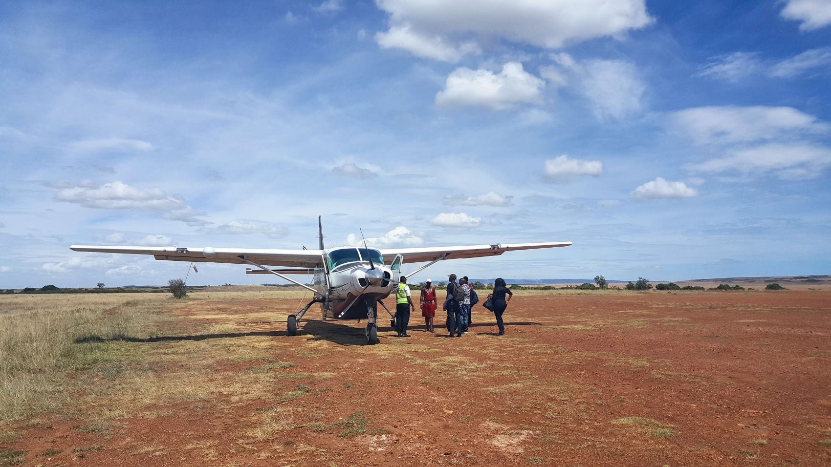 Passagiere beim Betreten eines Propellerflugzeugs auf dem Olkiombo Airstrip