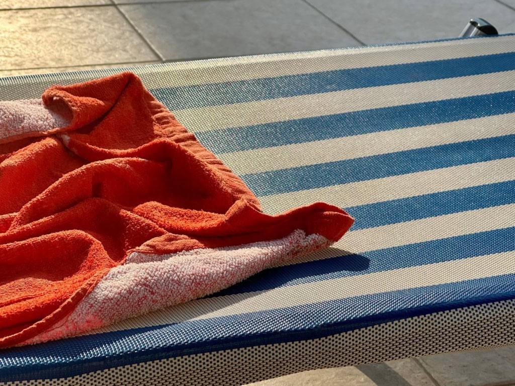 Reservierte Poolliege: Rotfarbenes Handtuch auf blau-weiß gestreifter Liege platziert