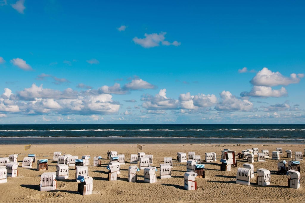 Auf der Ostfriesischen Insel Spiekeroog stehen zahlreiche Strandkörbe am Strand, bereit für den Urlaub.