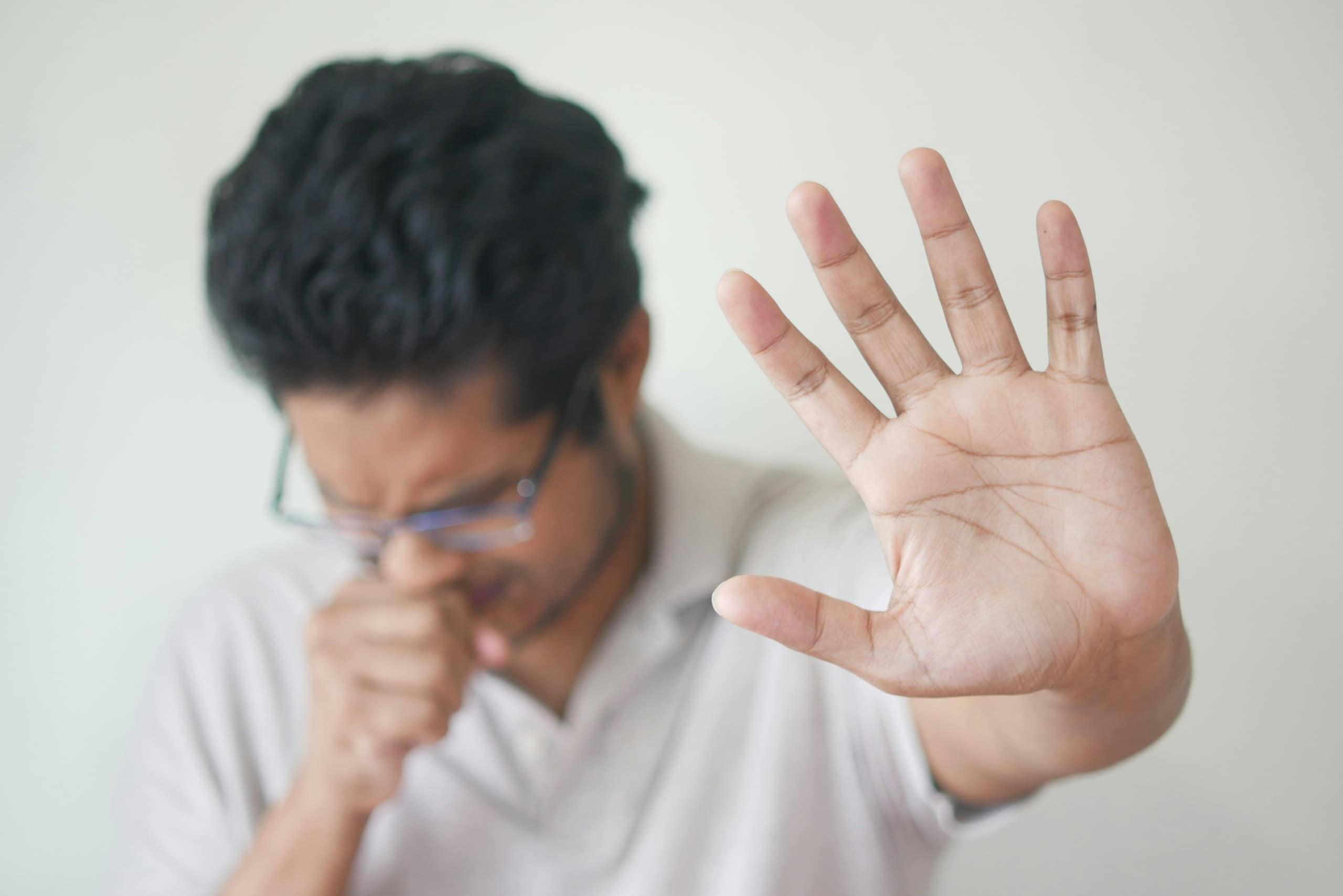 Ein Mann nimmt die Hand vor dem Mund weil er hustet