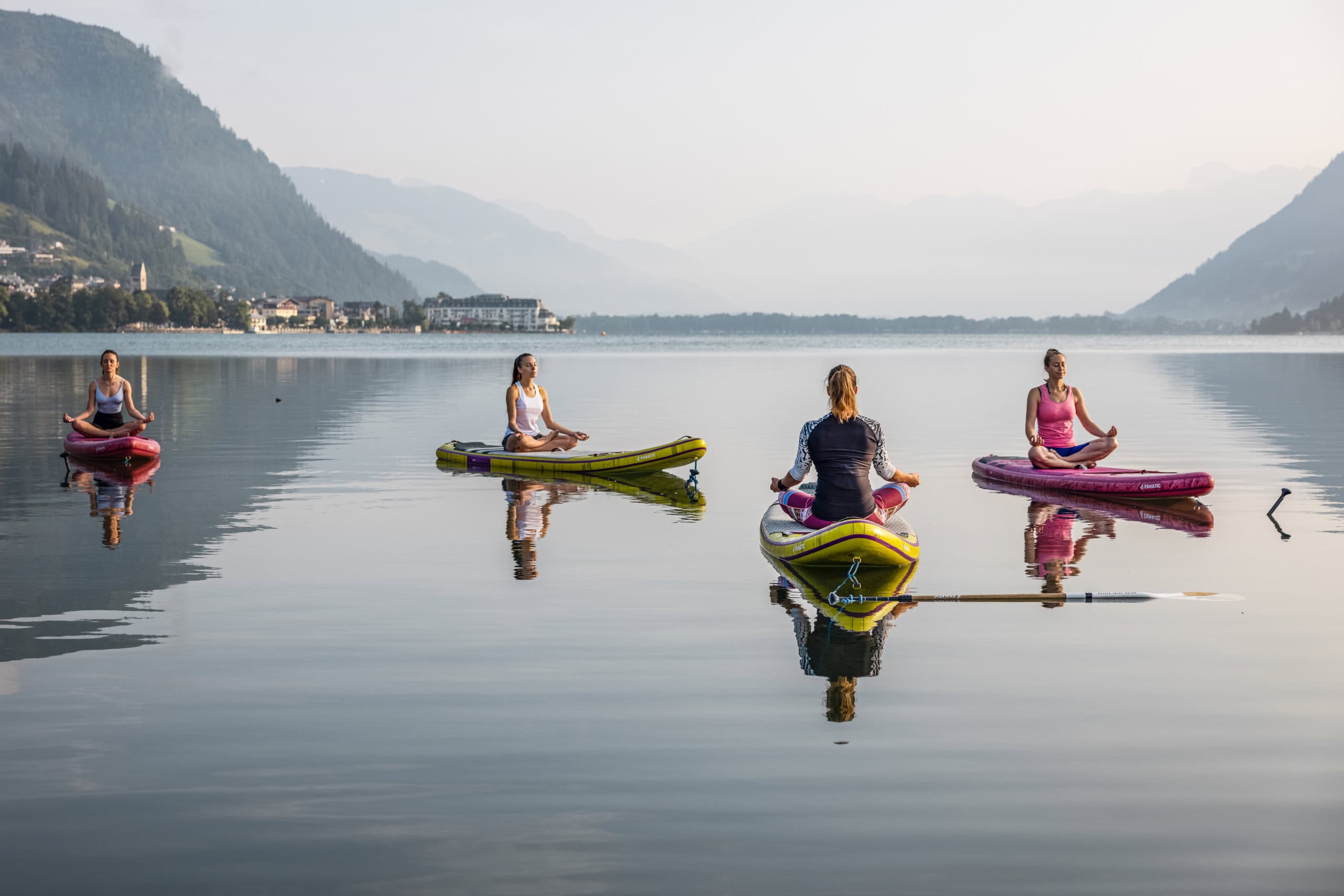 Vier Frauen machen auf dem Zeller See Yoga auf SUPs.