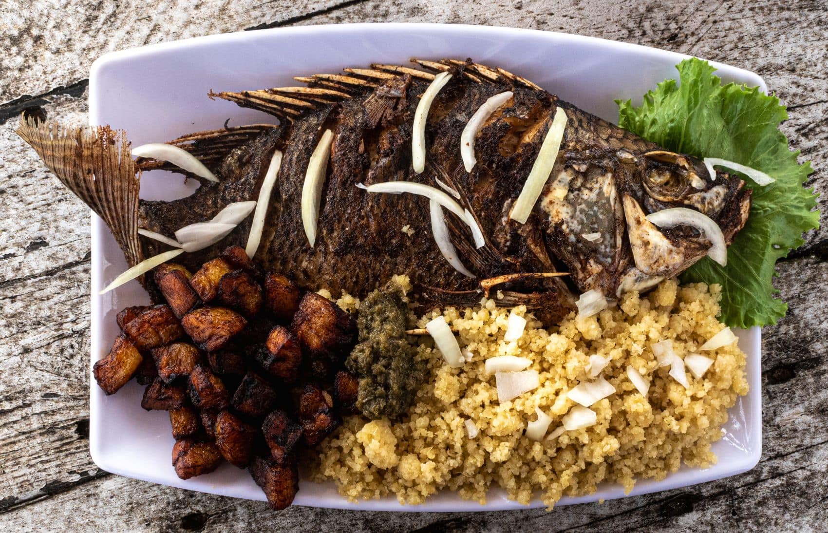 Attiéké mit Fisch auf einem Teller serviert 