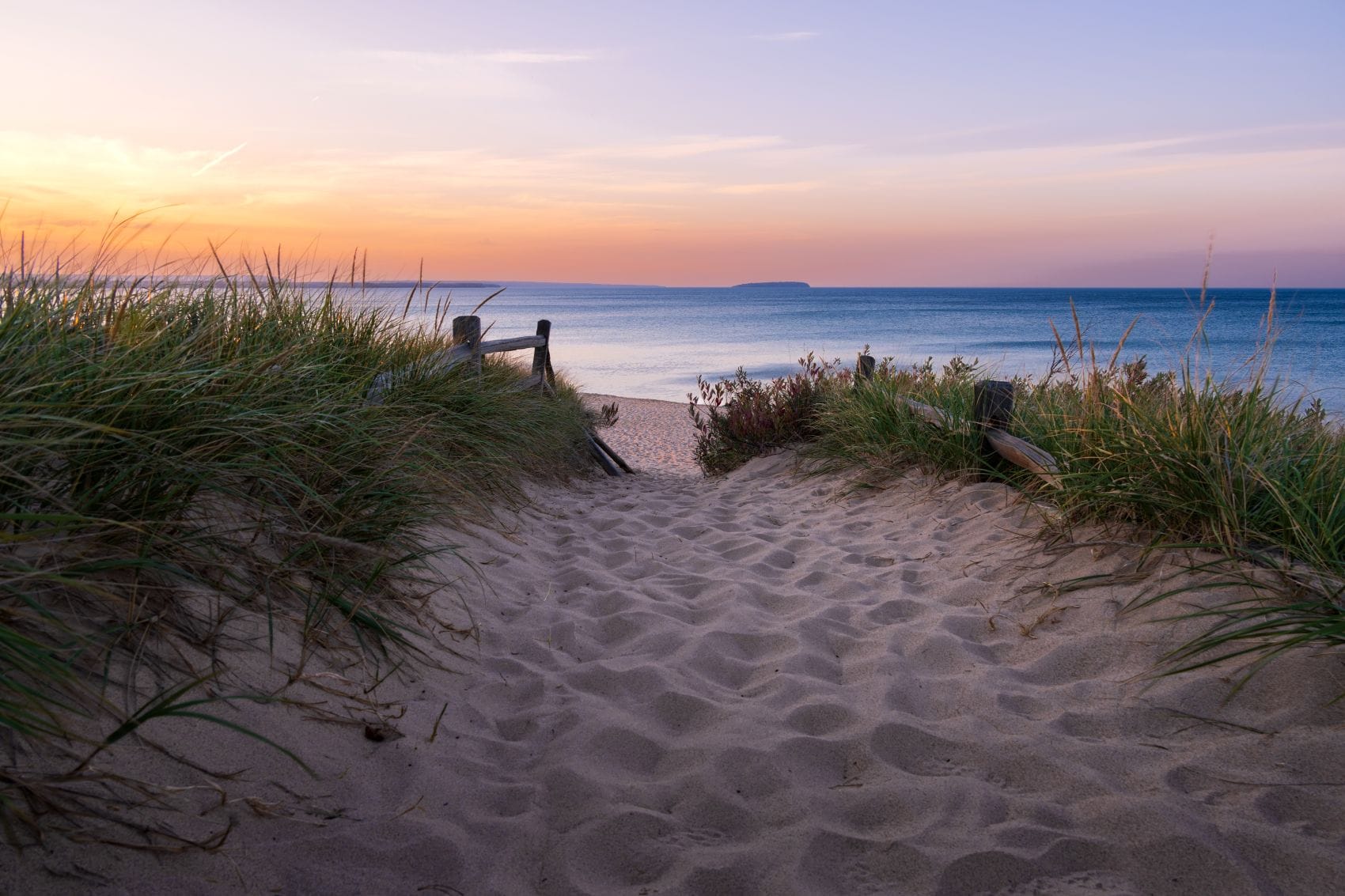 Sandweg durch Dünengras zu einem Strand am Lake Superior bei Sonnenuntergang in Michigan