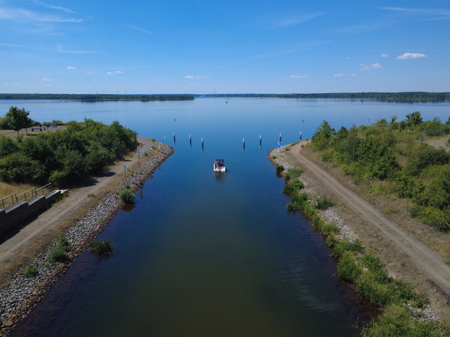 Luftaufnahme eines Bootes, das vom Koschener Kanal auf den weiten Senftenberger See hinausfaehrt.