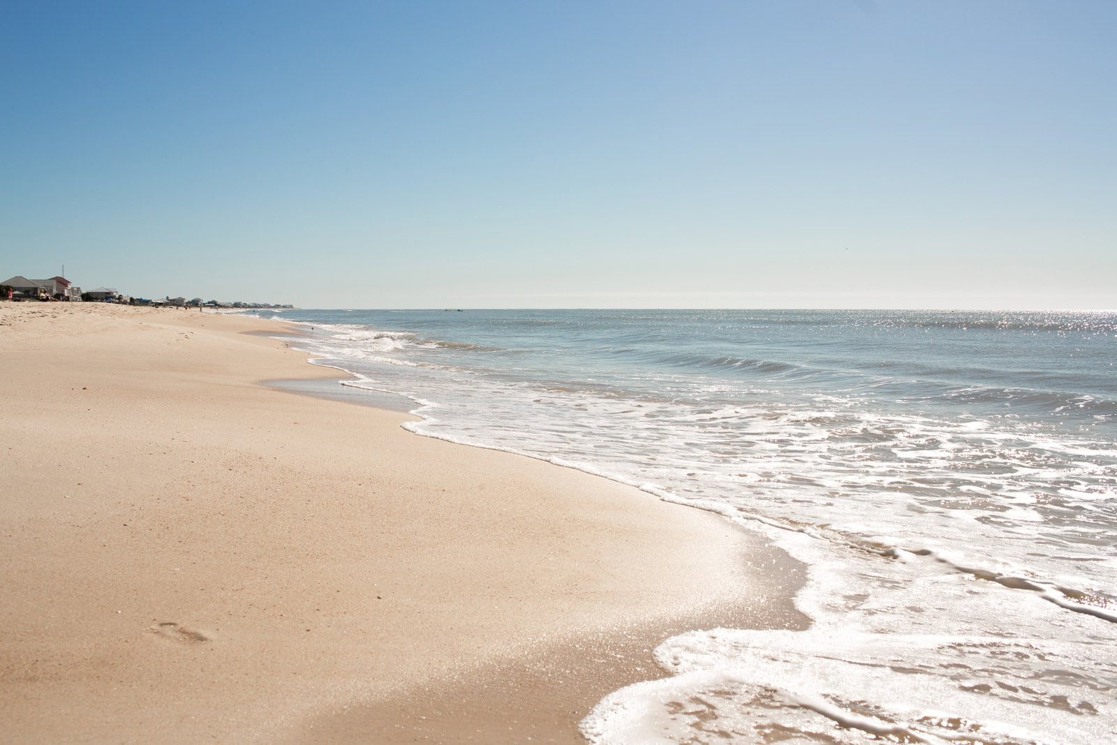 Menschenleerer, weiter Sandstrand auf St. George Island mit sanfter Brandung unter klarem blauem Himmel