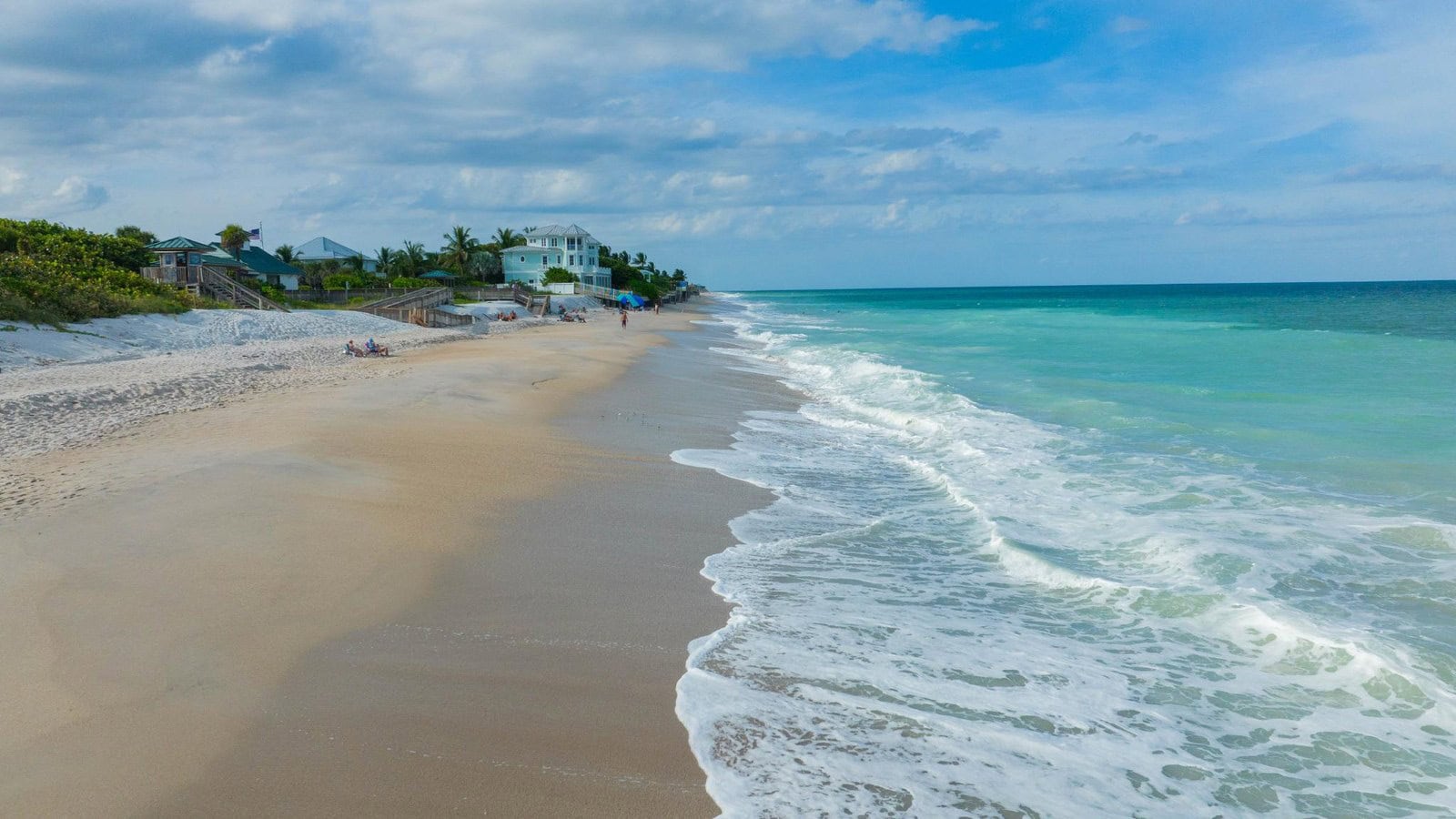Luftaufnahme des Wabasso Beach in Vero Beach mit türkisem Wasser, Brandung und Strandhäusern hinter den Dünen