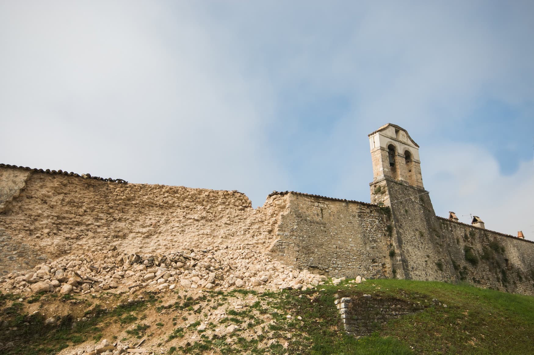 Eine mittelalterliche Mauer in Italien, die teilweise eingefallen ist, verursacht durch ein Erdbeben.