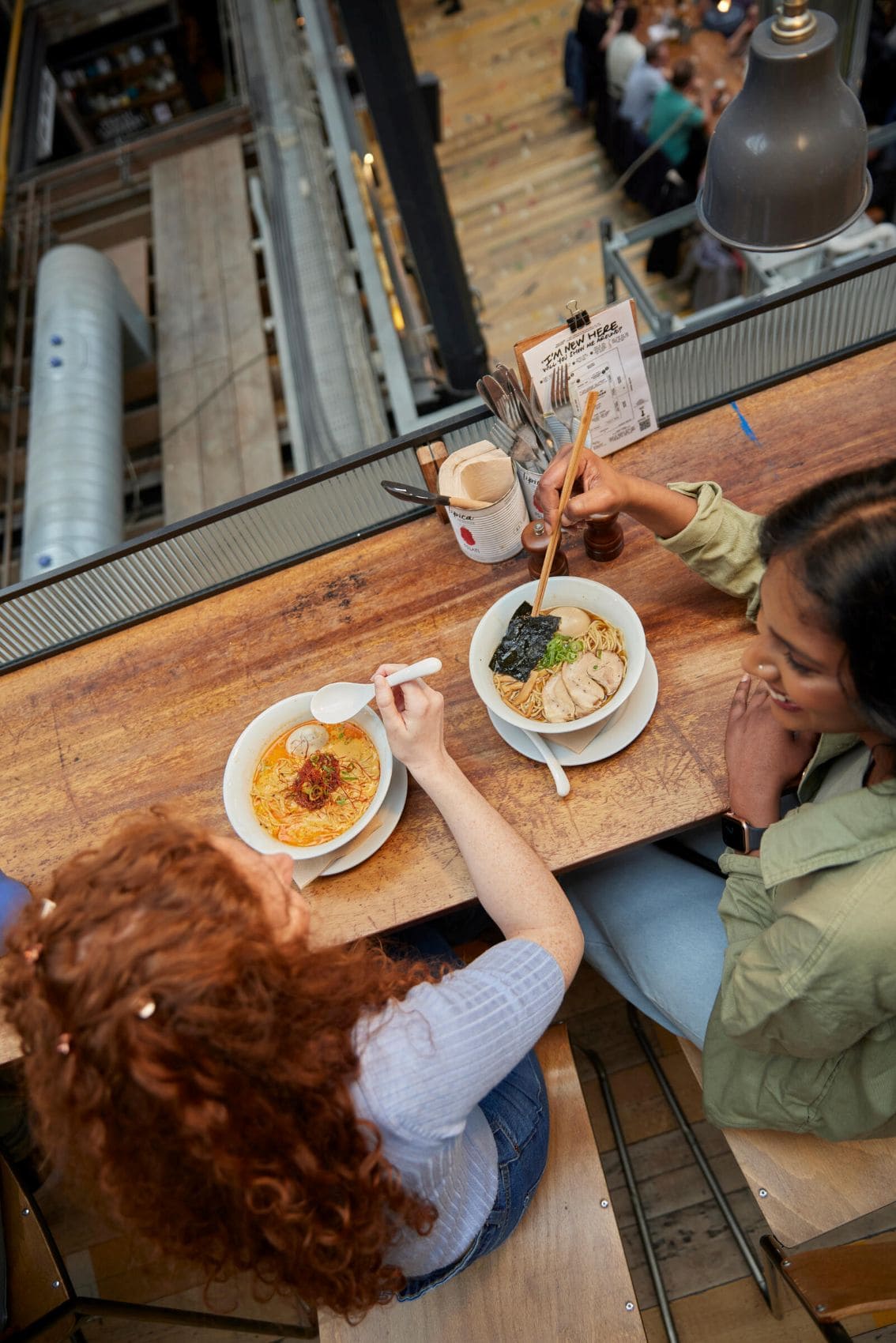 Zwei Frauen essen und lachen in der Markthalle Mackie Mayor im Zentrum von Manchester.
