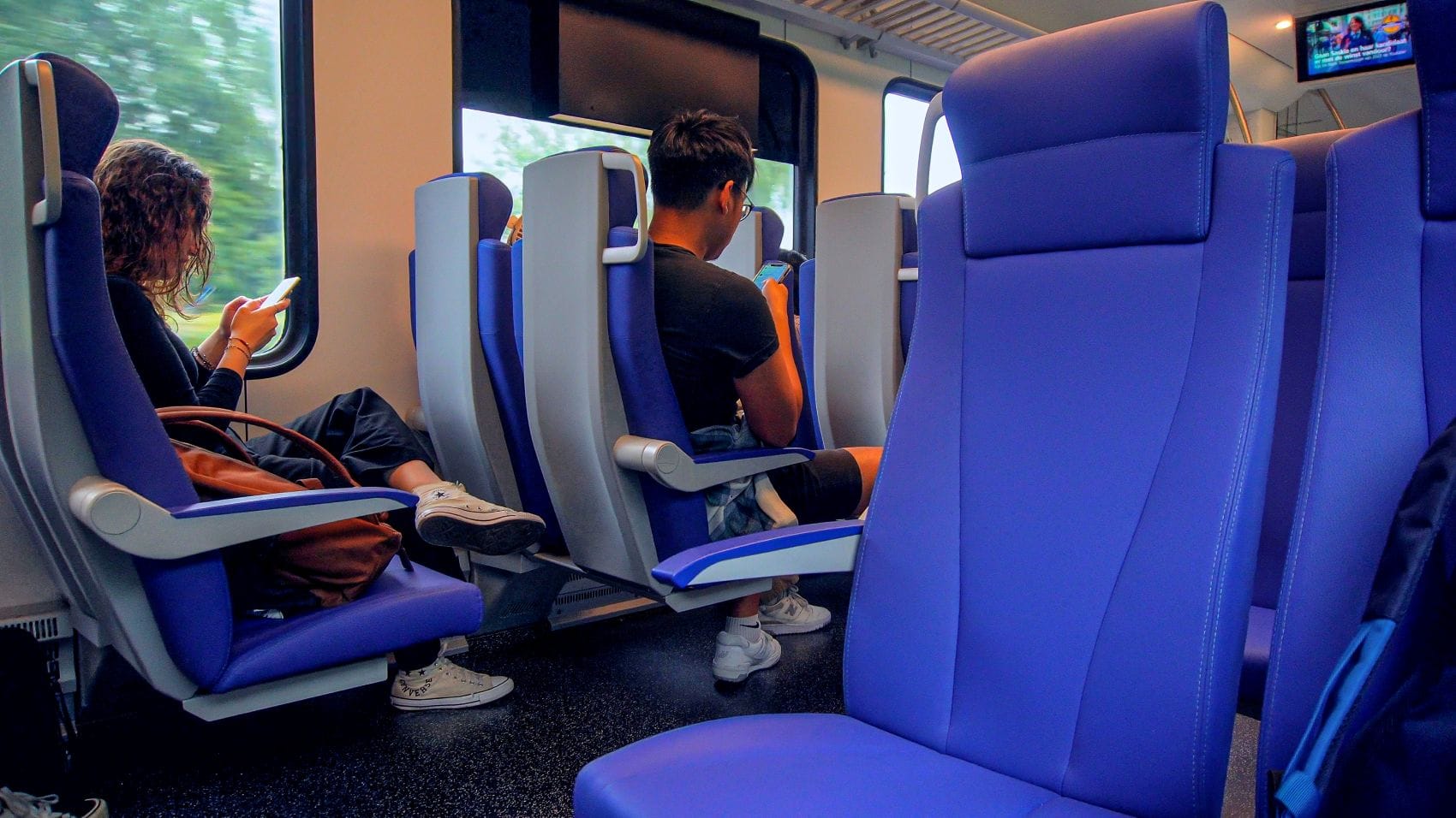 Junge Fahrgäste sitzen in einem Abteil eines Zuges in den Niederlanden 