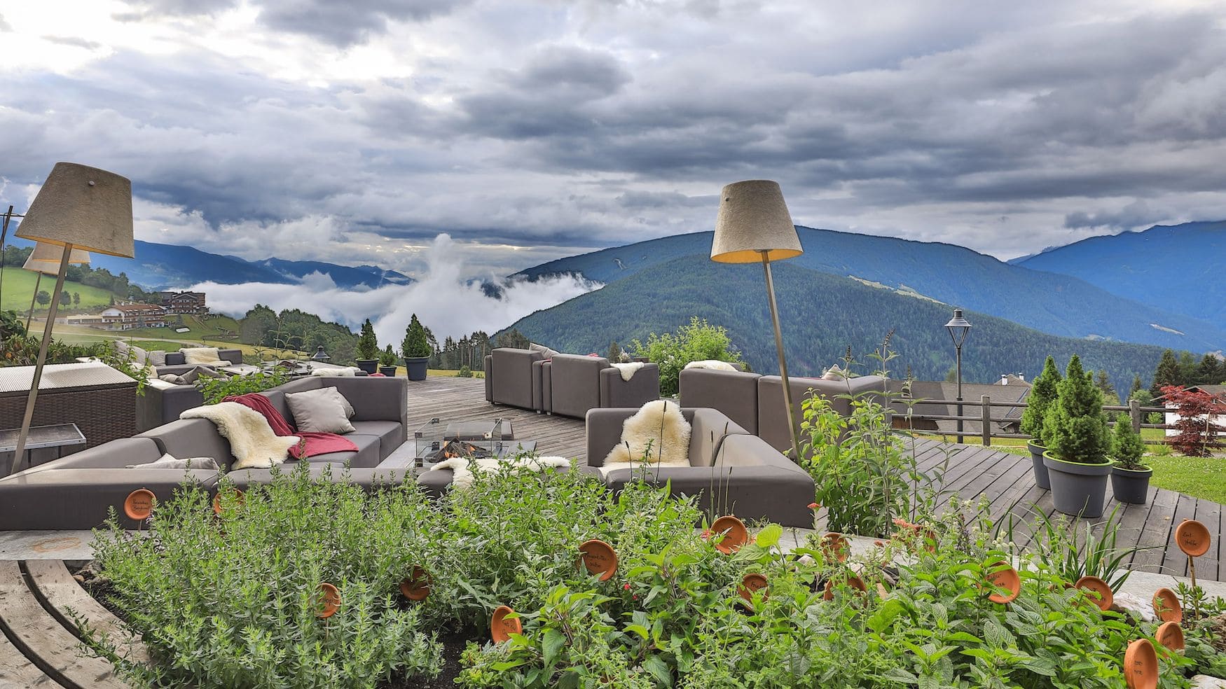 Lounge auf der Terrasse des Hotel Aui mit Sofas, Feuerstelle und Panorama über das Pustertal