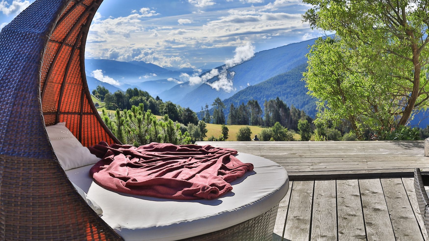 Rundes Daybed auf der Holzterrasse desHotel Aui mit Blick über das Pustertal