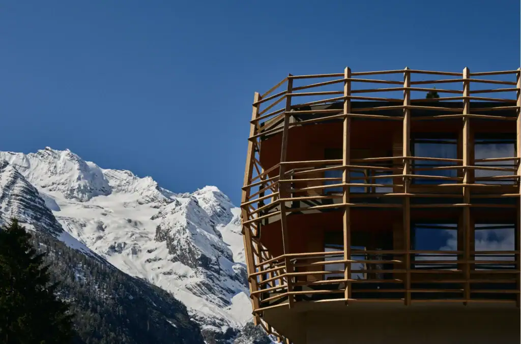 Detailansicht der gebogenen Holzlatten-Fassade des Matteo-Thun-Anbaus am Hotel Bella Vista vor dem verschneiten Ortlermassiv.