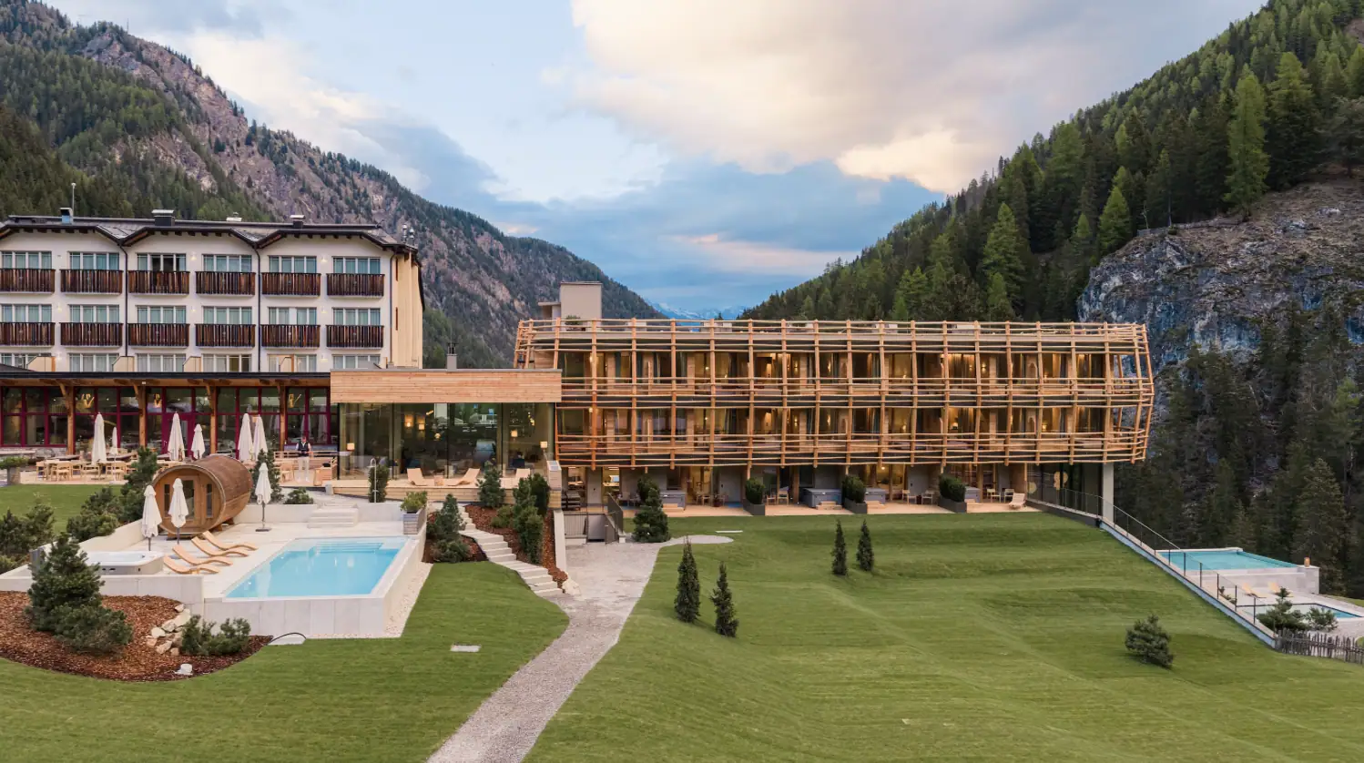 Vogelperspektive auf Hotel Bella Vista Trafoi mit neuem Holznest-Flügel von Matteo Thun, Außenpool und Infinity-Pool am Hangrand.