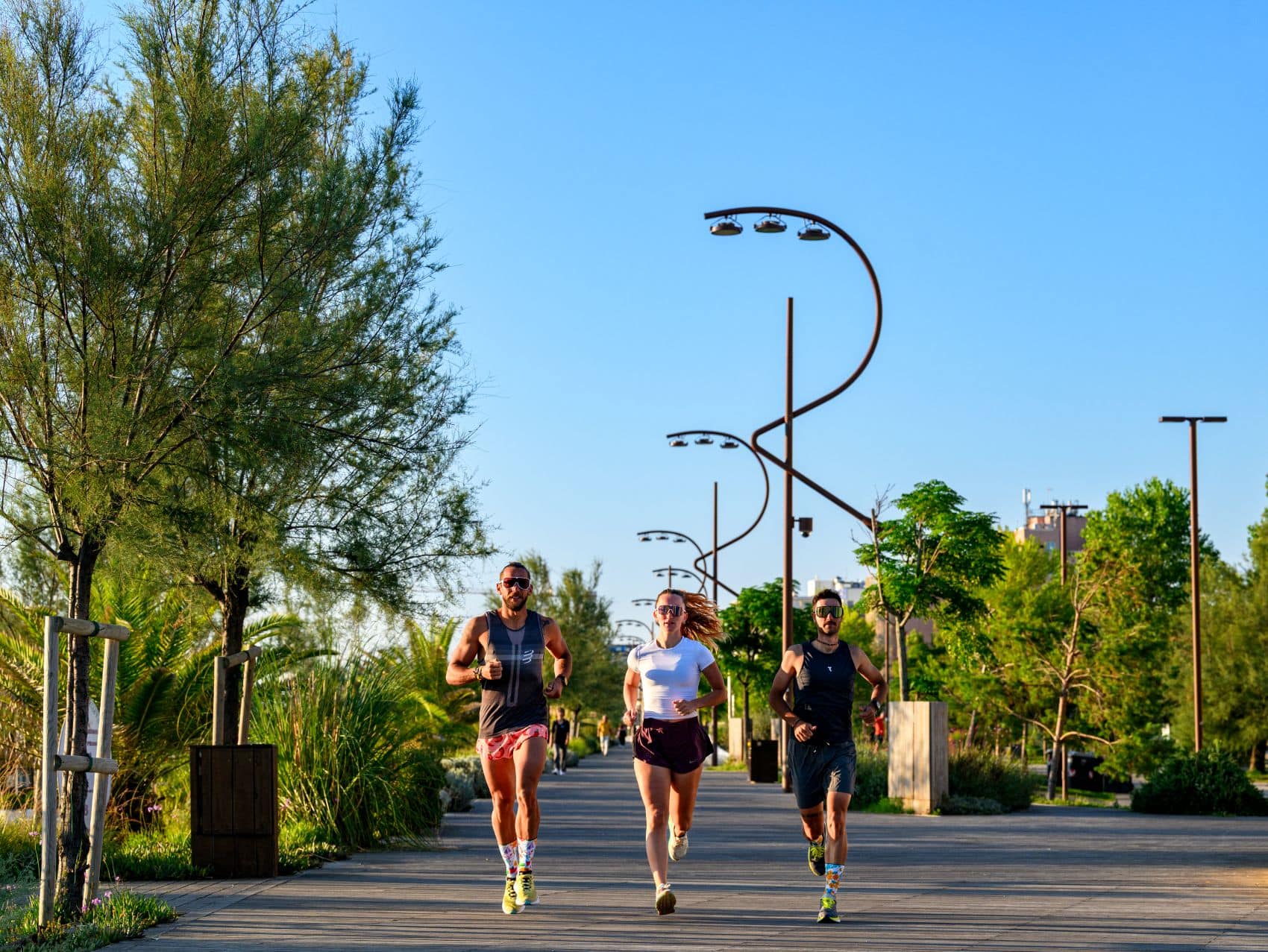 Zwei Männer und eine Frau joggen auf der Promenade in Rimini