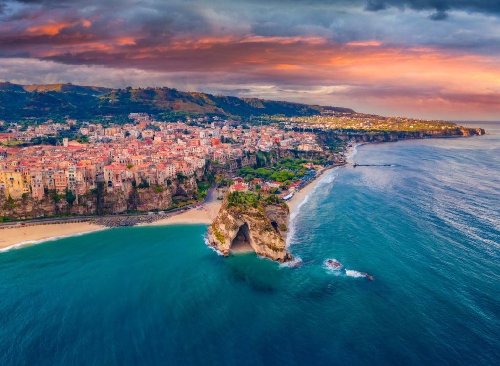 Die Stadt Tropea in Kalabrien mit der Drohne aufgenommen, im Licht der untergehenden Sonne. Am Horizont kündigt sich ein Regenschauer an.