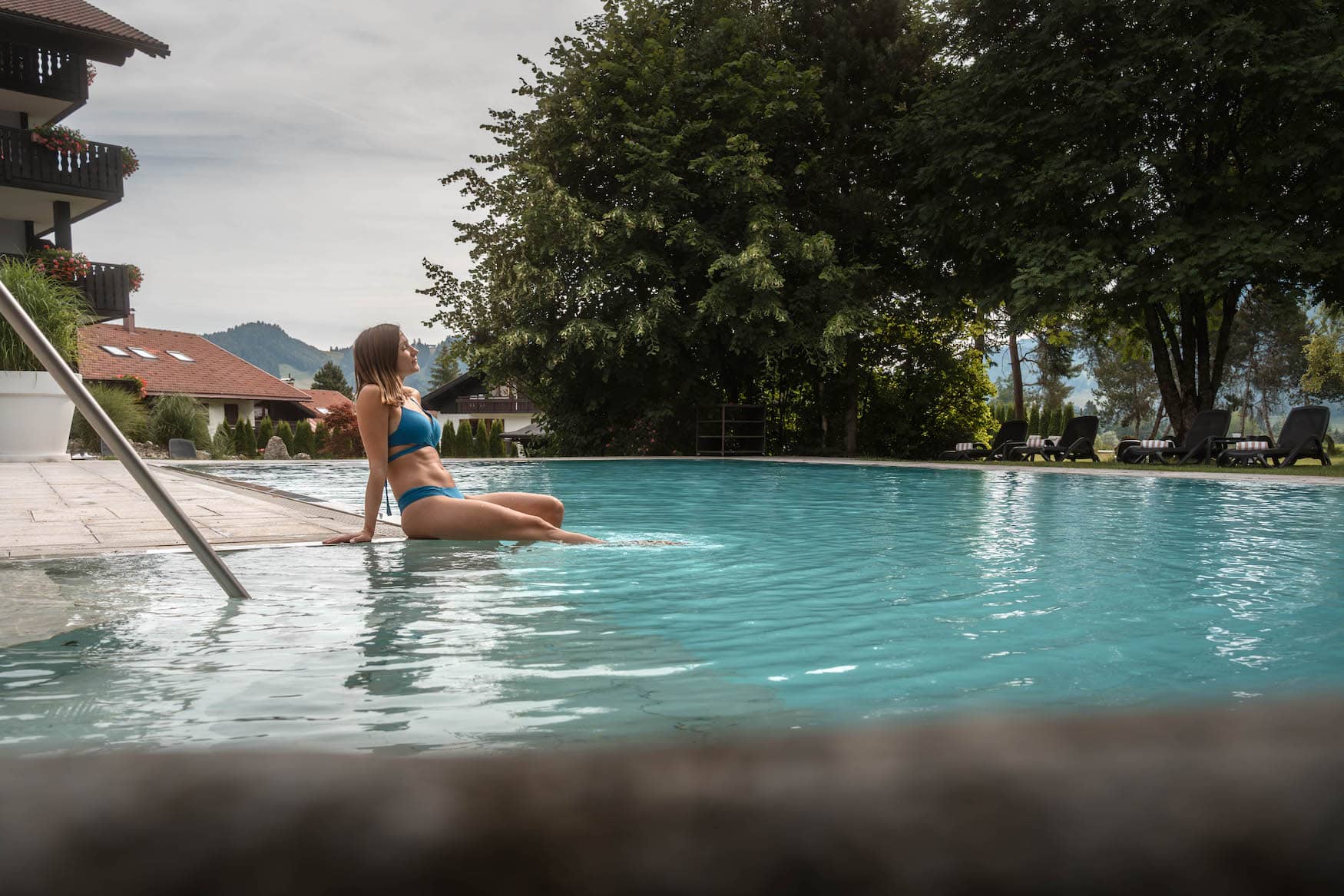 Frau am Außenpool des Ludwig Royal im Allgäu mit Bergpanorama im Hintergrund.