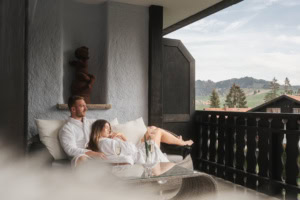 Pärchen im Bademantel auf dem Balkon des Ludwig Royal im Allgäu mit Blick auf die Berge.