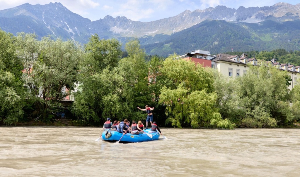 Teilnehmer einer geführten Rafting-Tour auf dem Inn vor der Kulisse der Innsbrucker Altstadt und der Nordkette in Tirol.