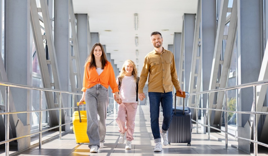 Familie mit Rollkoffern auf dem Weg zum Abflug im Flughafen-Terminal