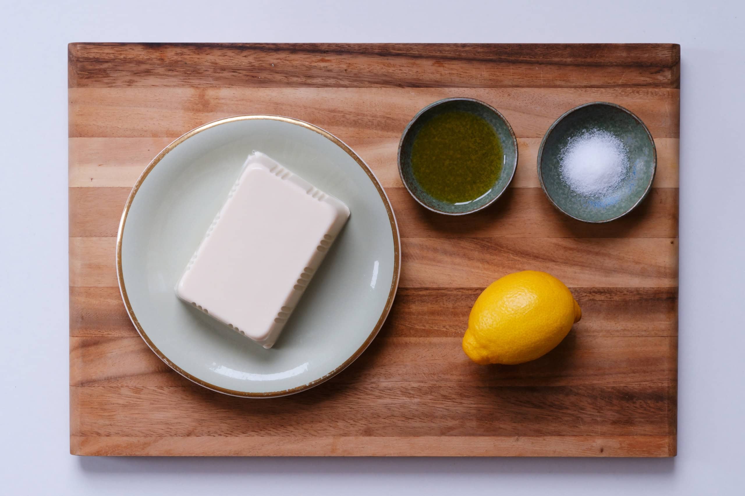 Zutaten für Tofucreme auf einem Brett: Seidentofu, Zitrone, Salz, Olivenöl