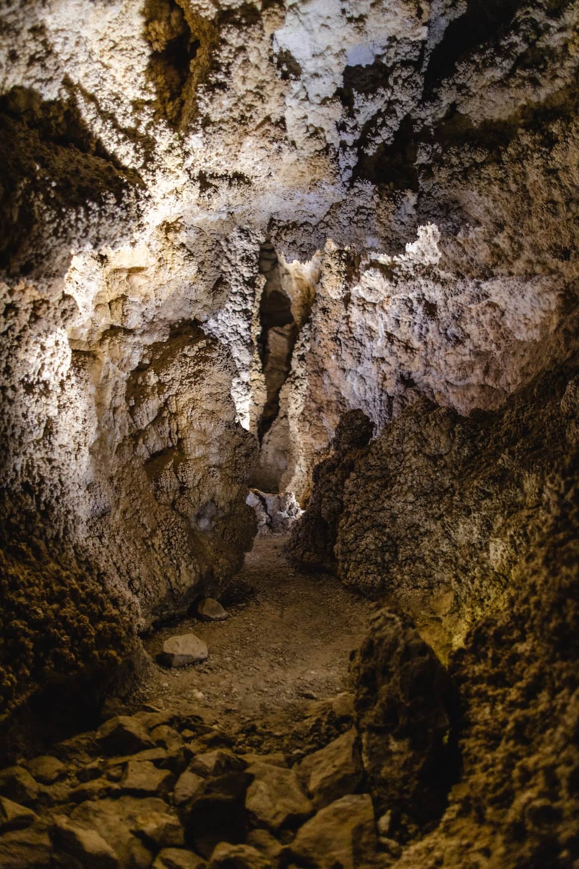 Enger Felsdurchgang in der Szemlő-hegyi-Höhle in Budapest mit weißen Mineralformationen an Wänden und Decke