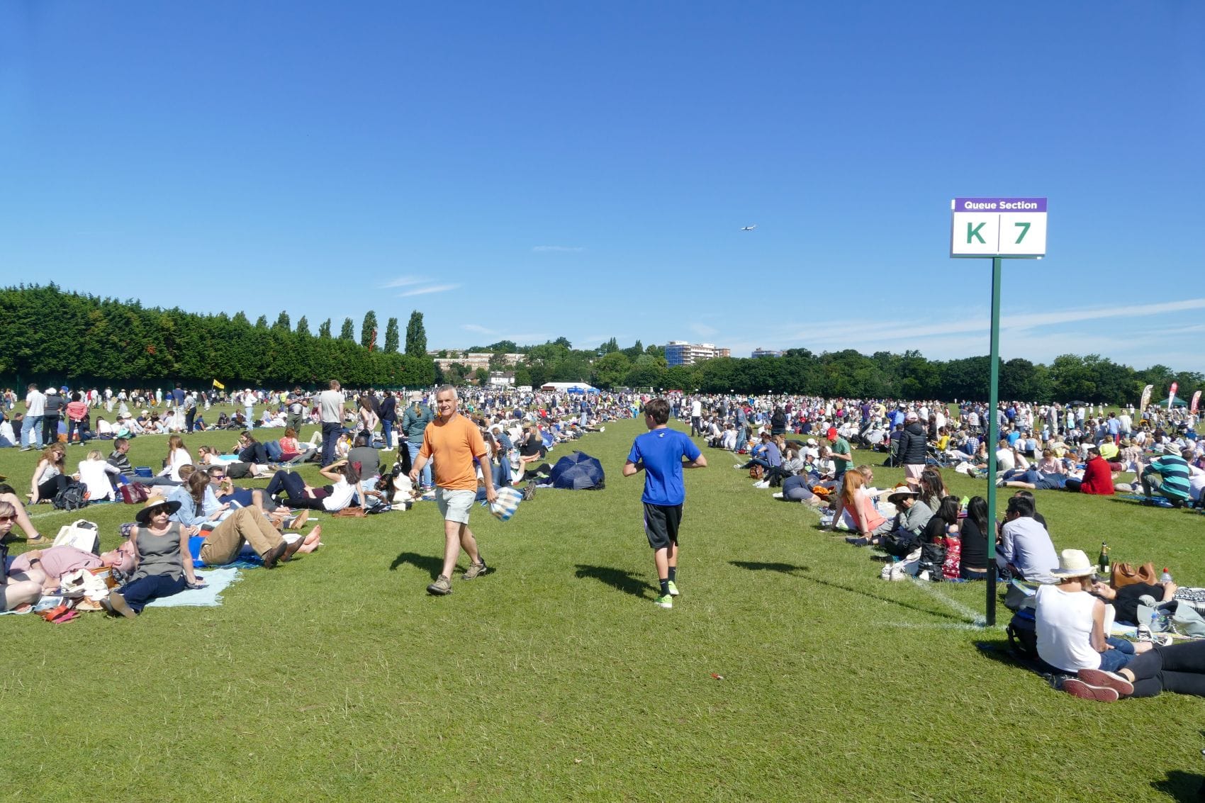 Besucher warten in Wimbledon auf einer Wiese