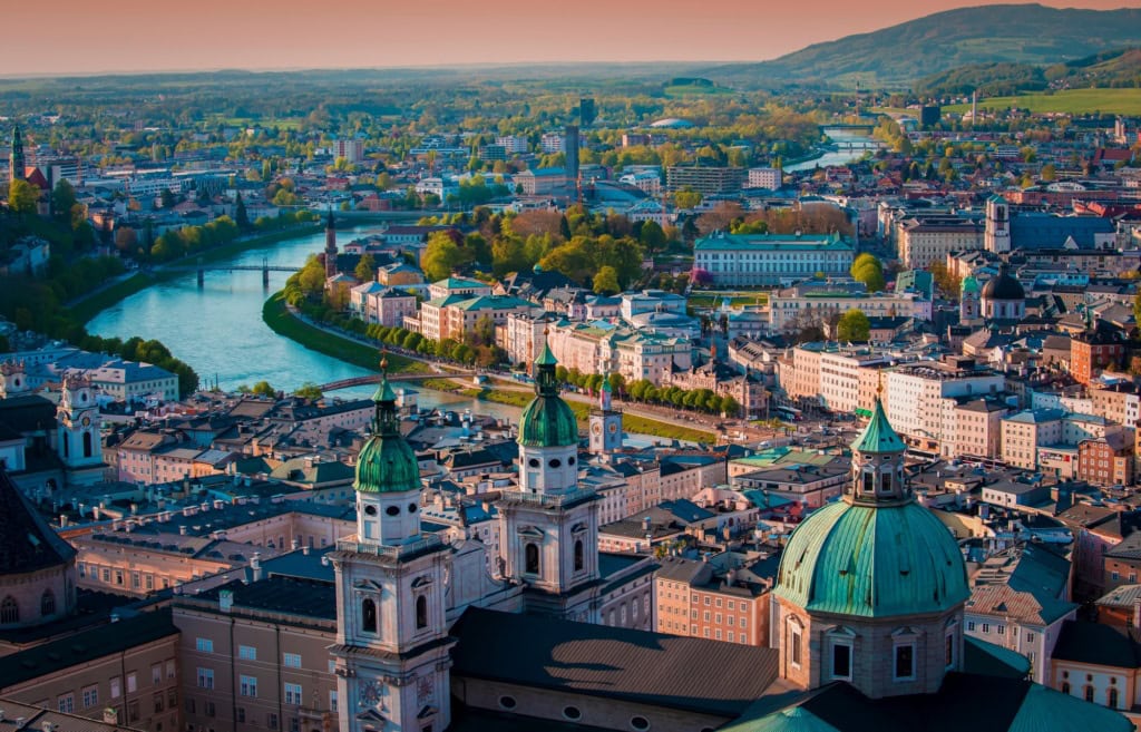 Luftaufnahme der Stadt Salzburg in Österreich im Abendlicht, mittig von der Salzach durchkreuzt